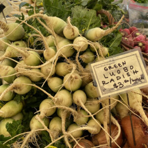 a pile of green radishes at the market.